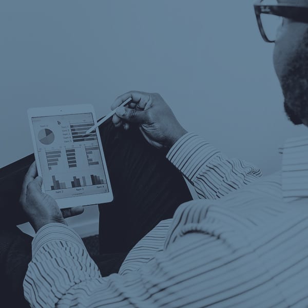 A man sitting with a tablet looking at data