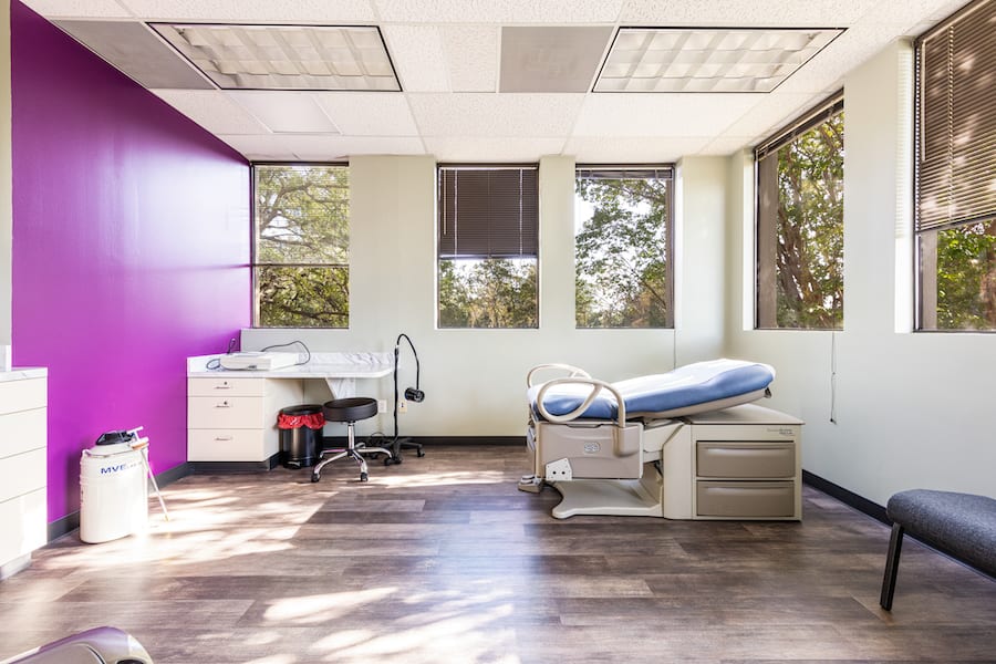 Medical office patient room with desk, chair, and examination chair.