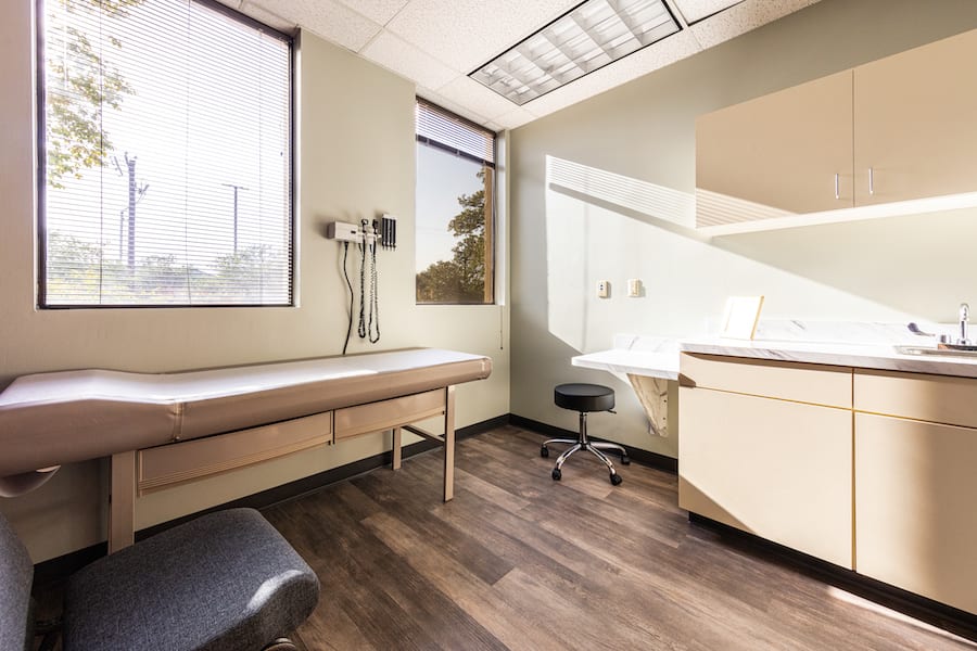 Medical office patient room with desk, chair, and examination table.